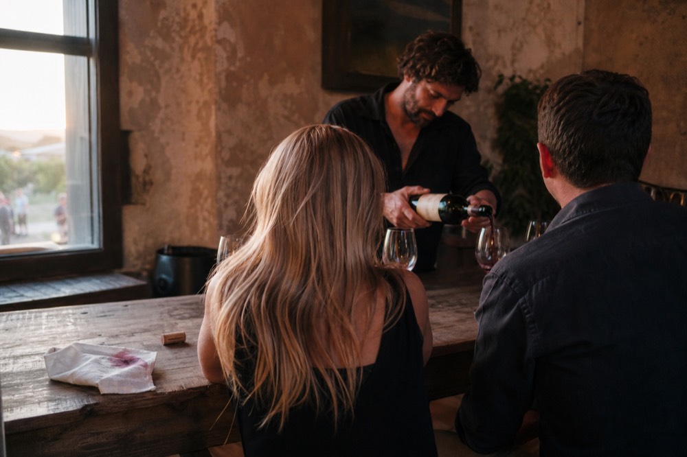 A tour guide pouring wine for guests at a Sonoma County tasting counter, no text, no logos, no people