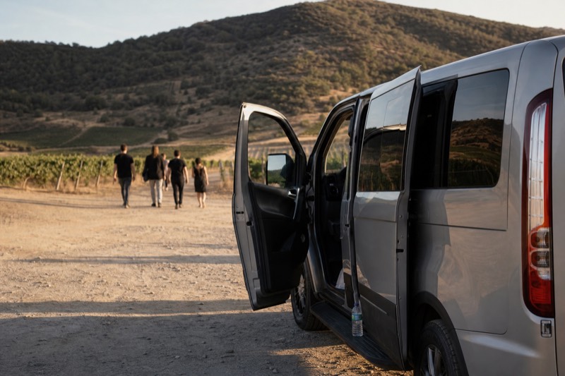 Tour van parked beside hillside vineyards in Sonoma wine country in late afternoon light