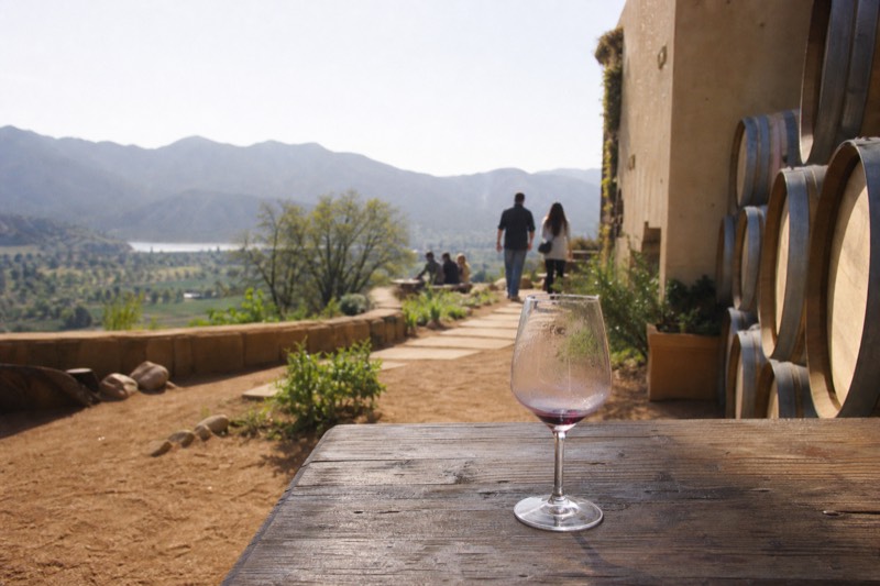 Sonoma Valley winery patio with stacked oak barrels and a tasting glass on a wooden table
