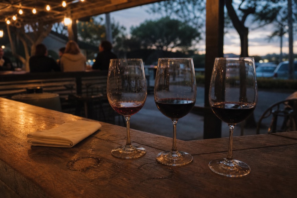 Tasting flight of red wines on a winery bar counter, no text, no logos, no people