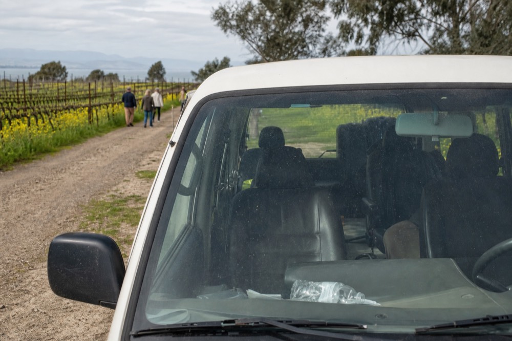 A small group wine tour van parked in front of a scenic winery, no text, no logos, no people
