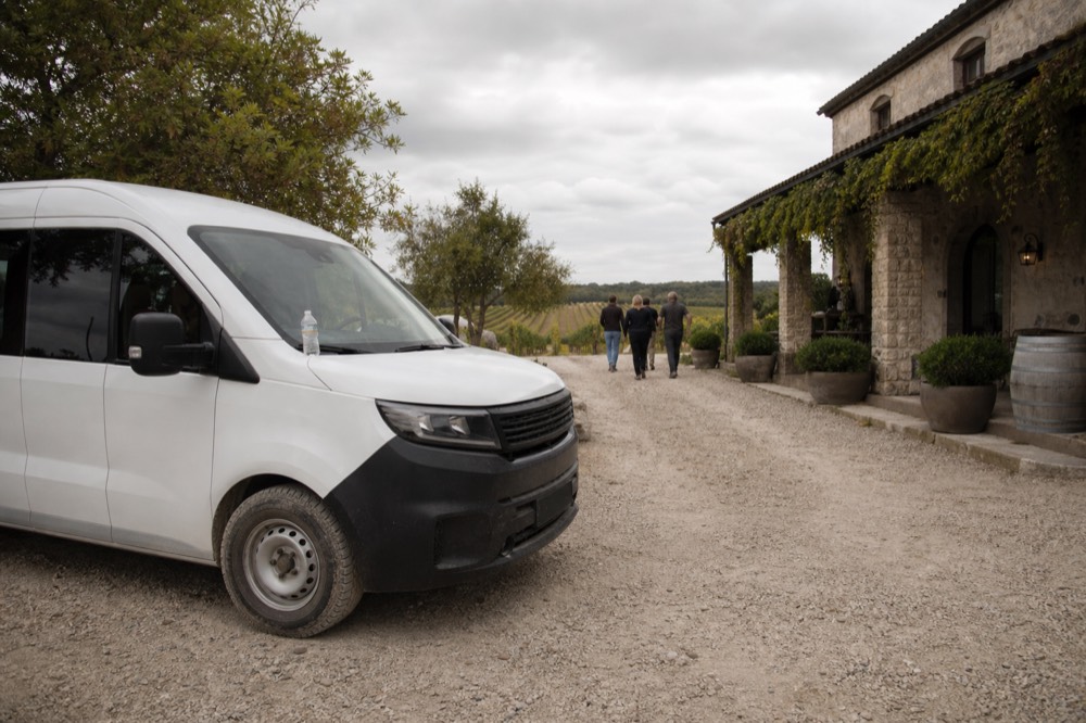 Small van parked on a gravel drive beside a boutique winery tasting room, no text, no logos, no people