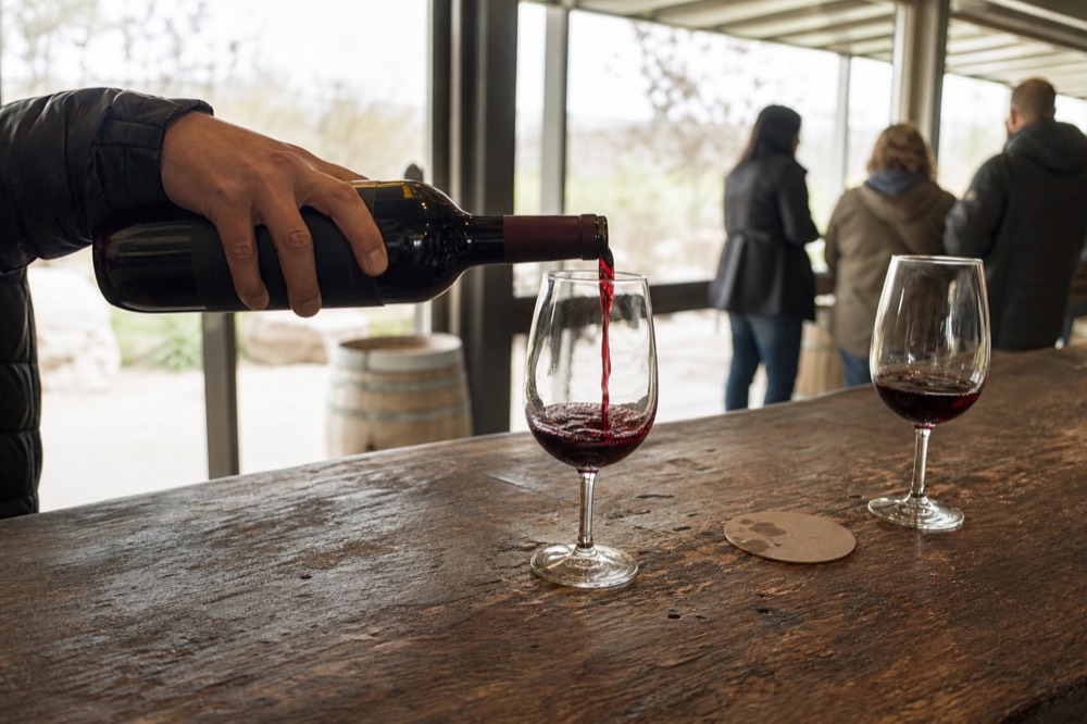 A pour of red wine into a glass at a Sonoma tasting room bar, no text, no logos, no people